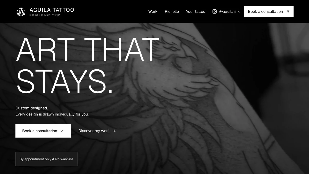 AGUILA Tattoo's homepage, with a large light-weight headline over a monochrome eagle tattoo video, a consultation link, and an appointment-only notice